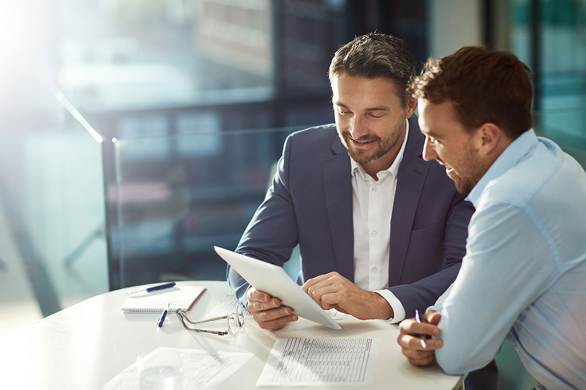 A business professional and client discuss a spreadsheet while seated at a small table.